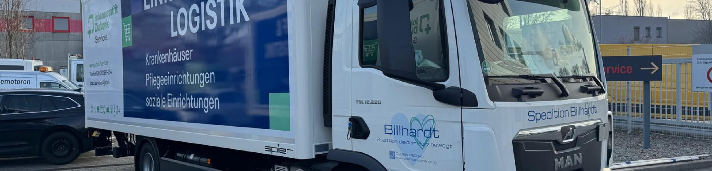 Lieferwagen mit Werbung für Logistikdienstleistungen auf einem Parkplatz.